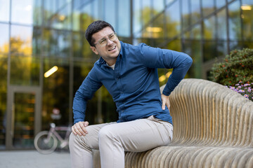 Man experiencing discomfort from lower back pain while seated outdoors