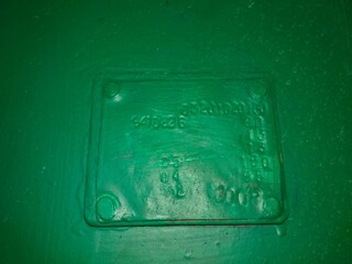 A Green Surface Features a Rectangular Sign With Embossed Text Indicating Identification Details
