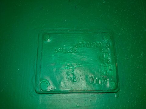 A Green Surface Features a Rectangular Sign With Embossed Text Indicating Identification Details