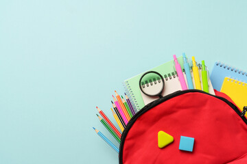 School backpack with stationery on colored background.