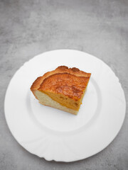 Slice of pumpkin pie showing its filling on white plate, autumn dessert