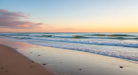 Fototapeta premium Gentle ocean waves softly kiss a tranquil sandy beach at golden hour sunrise