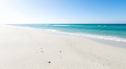 Serene white sand beach with gentle turquoise waves under a clear blue sky