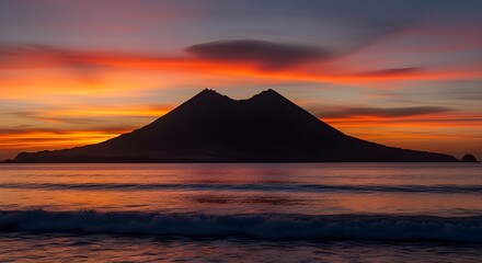 Stunning volcanic silhouette against a fiery sunset over the ocean with gentle waves crashing ashore