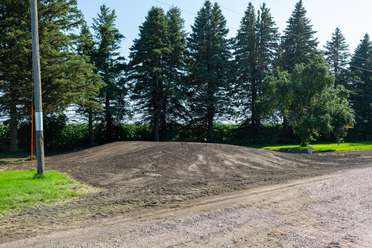 Septic system mound installation with fresh dirt earthwork on a rural property landscape