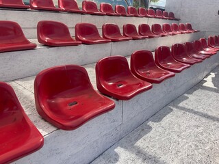 A close-up view of empty, red stadium seats arranged in rows on a set of bleachers, showcasing the repetitive pattern and glossy texture perfect for designing a sports or entertainment venue
