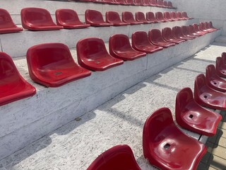 A close-up view of empty, red stadium seats arranged in rows on a set of bleachers, showcasing the repetitive pattern and glossy texture perfect for designing a sports or entertainment venue