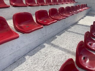 A close-up view of empty, red stadium seats arranged in rows on a set of bleachers, showcasing the repetitive pattern and glossy texture perfect for designing a sports or entertainment venue