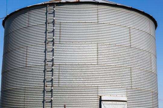 Close-Up of Weathered Metal Grain Bin & Ladder Under a Blue Sky &ndash; Agriculture and Harvest Concept &ndash; Rural Farm Architecture