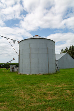 Weathered Metal Grain Bin Standing on Farm Field &ndash; Agriculture and Harvest Concept