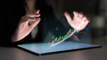 A professional business person uses a tablet to analyze financial data with 3D charts in a dark office environment, emphasizing technology and growth. Impute