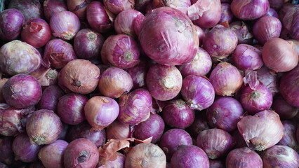 Bin packed with purple tinted red onions with papery skins