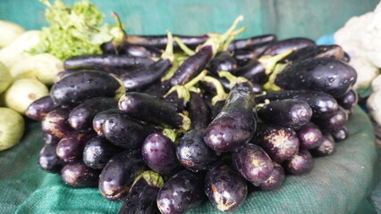 Pile of glossy dark eggplants with green stems attached