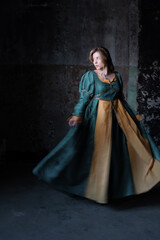 Fair-haired noble in hunter-green historical gown, poised elegantly before castle-style backdrop
