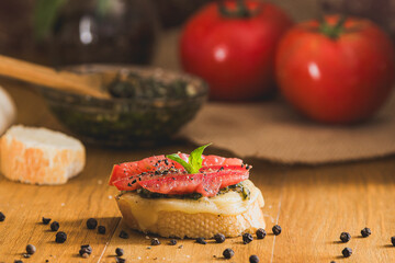 Bruschetta with tomato, cheese, pesto topped with fresh basil leaves