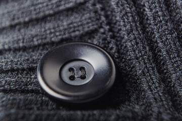 Close-up of black button on knitted dark fabric