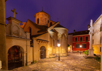 Night view of the Armenian Cathedral in Lviv, Ukraine, with warm lighting and cobblestone courtyard