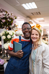 Two happy female florists embracing in a flower shop