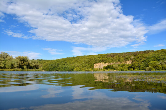Landscape of a tranquil lake reflecting the sky and wooded hills