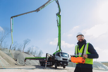 Construction worker operating concrete pump truck at plant
