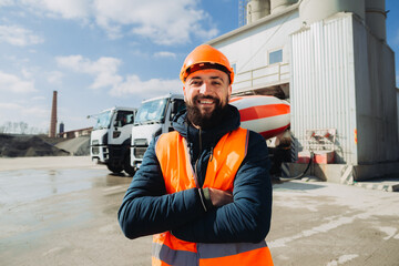 Construction worker smiling with crossed arms at concrete production plant