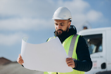 Engineer reading blueprint at concrete production plant