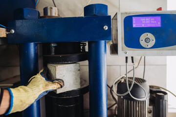 Concrete testing machine applying pressure on cube sample in laboratory