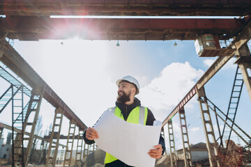 Construction engineer examining blueprints at concrete production plant