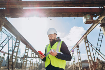 Construction engineer using smartphone at concrete production plant