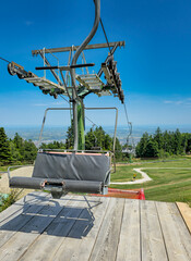 Close-up of cable car seat and wooden boarding platform, with mountain view, green meadow, and...