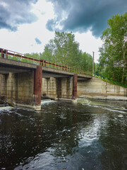 Panorama view from the riverbank with a bridge and dam on a cloudy day
