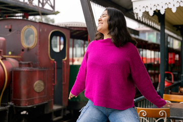 Young woman relaxing at train station with steam locomotive