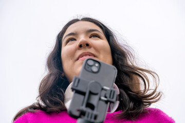 Young woman recording video content with smartphone and gimbal stabilizer outdoors