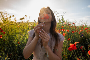 Woman practicing mindfulness in a poppy field at sunset. Concept of serenity, wellness, and...
