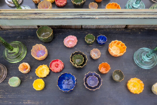 Cuencos de cer&aacute;mica coloridos para la decoraci&oacute;n del hogar, parte de ellos reflejados en un espejo superior, dispuestos sobre una superficie negra