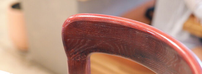 Detailed close-up of a polished dark red wooden chair back. Macro shot showing the glossy finish...