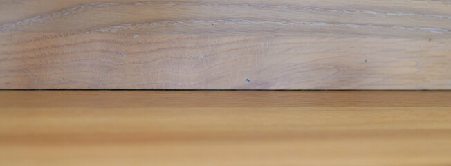 Detailed close-up of a natural wood plank with a prominent grain texture. Abstract background showing two different wooden surfaces for design.