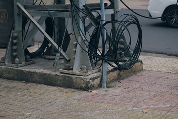 Industrial metal tower base with tangled electrical wires and cables on a concrete foundation on an...