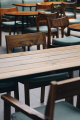 Tilted perspective of empty restaurant with chairs stacked on tables. Wooden furniture creating a repeating pattern in a closed establishment.