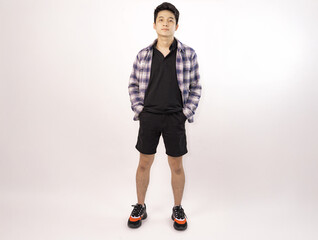 young man posing casually in trendy outfit against a plain background