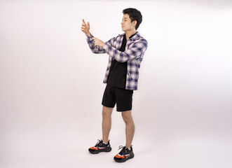 young man posing casually in trendy outfit against a plain background
