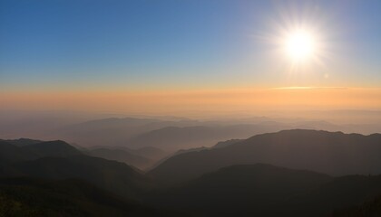 Obraz premium Sunrise over a misty mountain range, a tranquil vista from a high elevation.