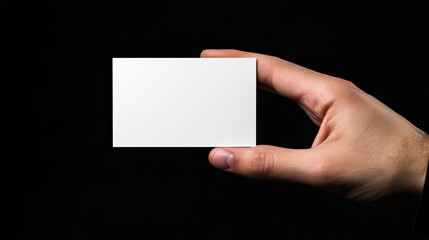 Hand holding blank white card on dark background