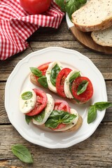 Delicious sandwiches with mozzarella cheese, tomatoes and basil on wooden table, flat lay