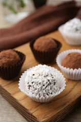Delicious homemade candies with cocoa powder and coconut flakes on table, closeup