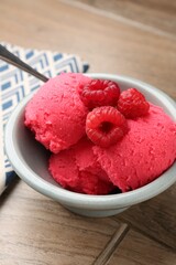 Delicious raspberry sorbet with fresh berries in bowl on wooden table, closeup
