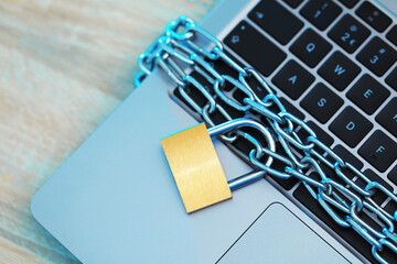 Cyber safety. Metal padlock with chain and laptop on table, above view