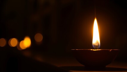 Golden diya glowing in darkness, symbolizing tradition and festive spirit in Indian culture.