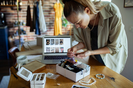 Young woman packaging jewelry for online second hand store at home