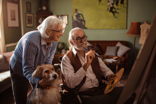 Senior couple spending time together painting with dog at home